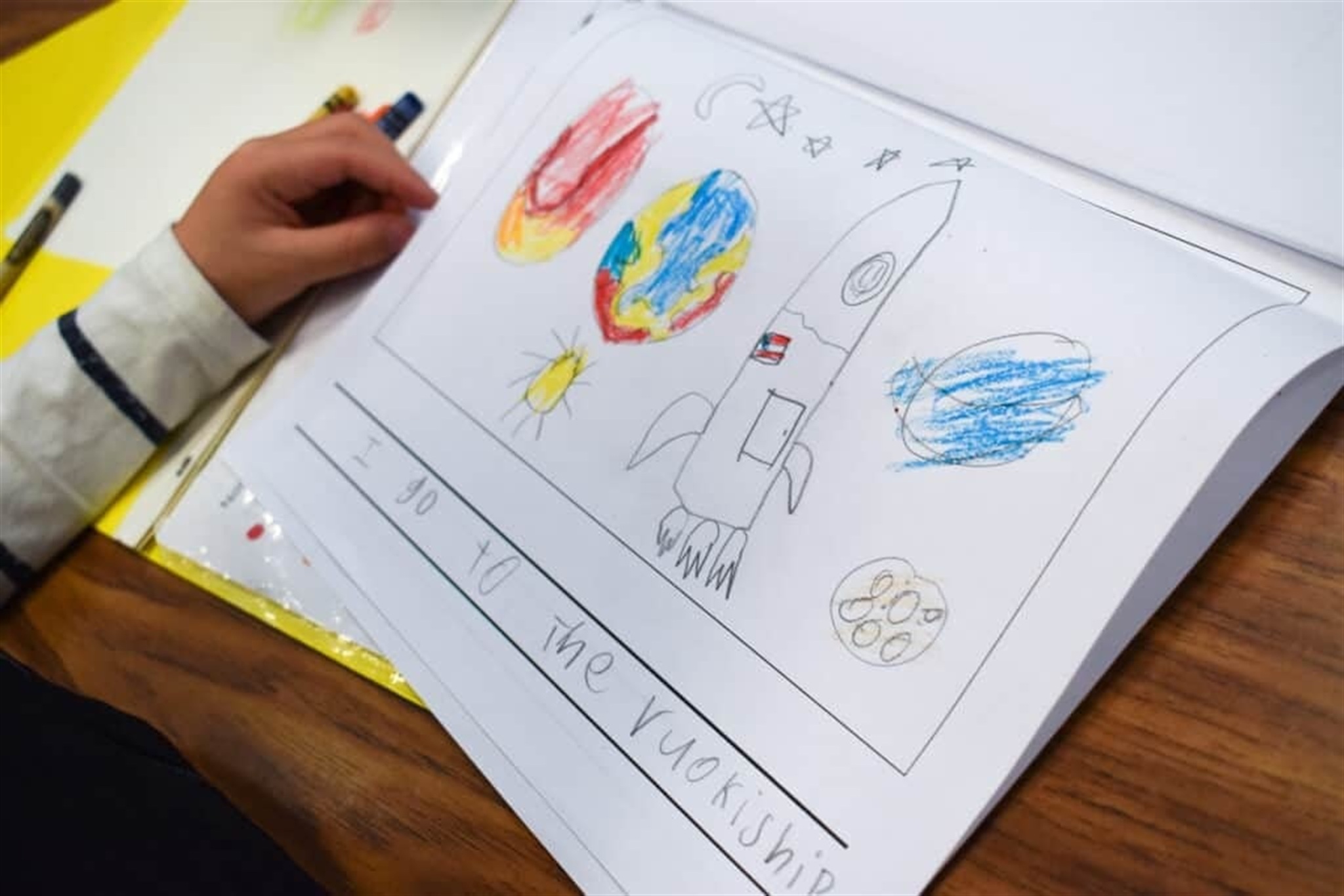 A young student drawing and writing on paper